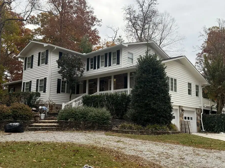 White horizontal lap siding and black shutters on a two-story house, siding painting in Knoxville, TN by Castle Painters